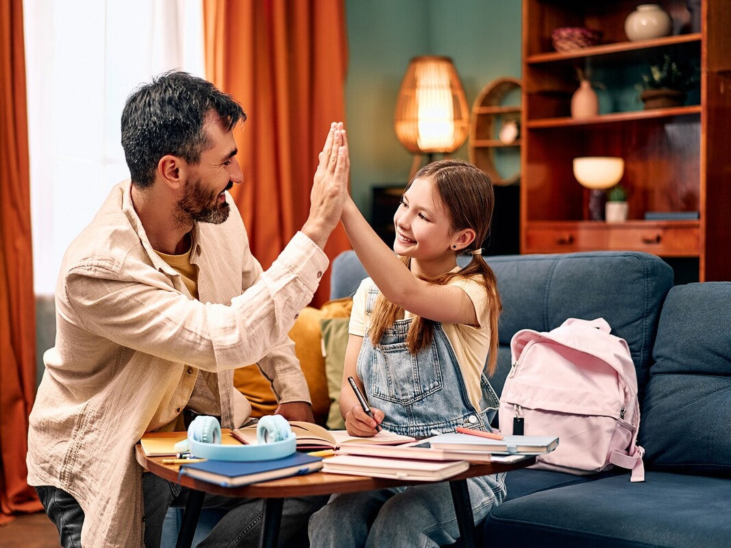 dad helping his daughter do the best summer workbooks for kids