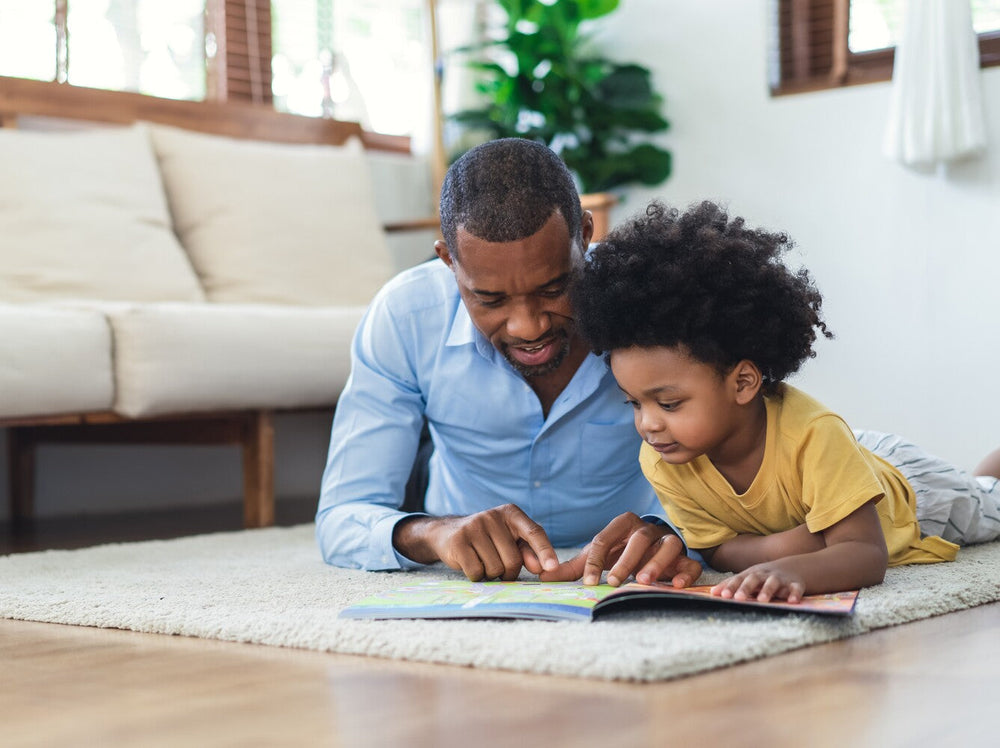 dad showing the benefits of reading aloud to children by reading a book to his son at home