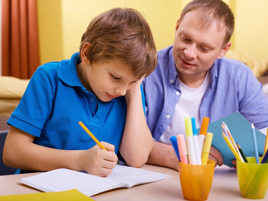 father helping his son work through the best 2nd grade workbooks