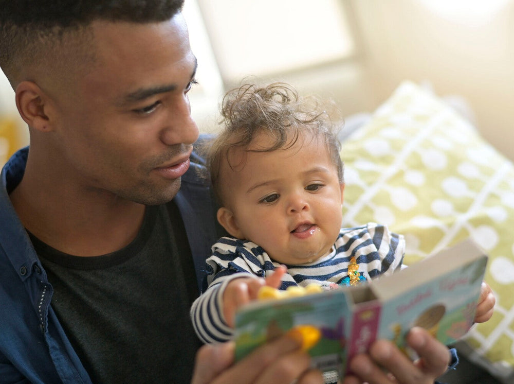 father showing when to start reading to a baby by reading to his baby girl at home
