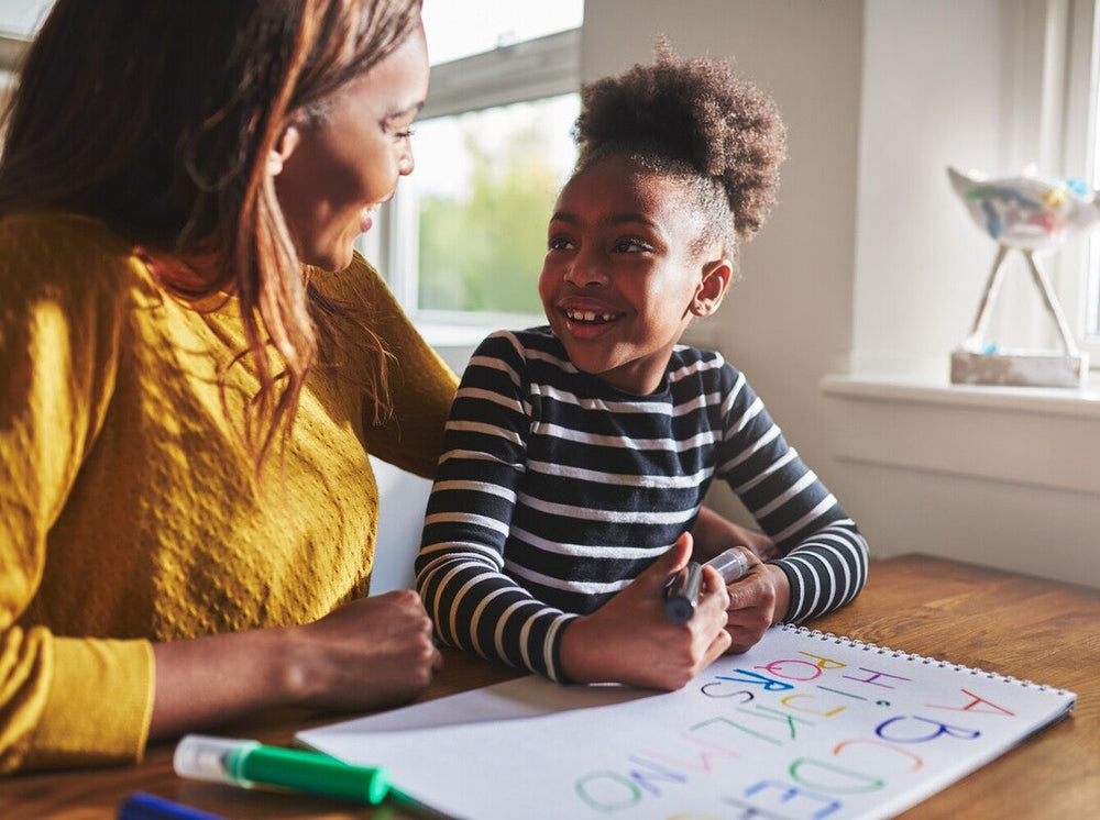 mother showing her daughter creative ways to practice spelling words by using colorful markers