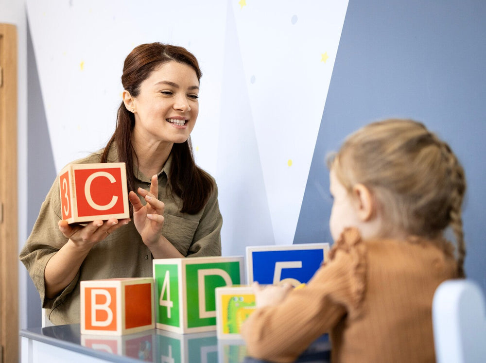 teacher showing an example of when do kids learn the alphabet by teaching a young girl letters using blocks