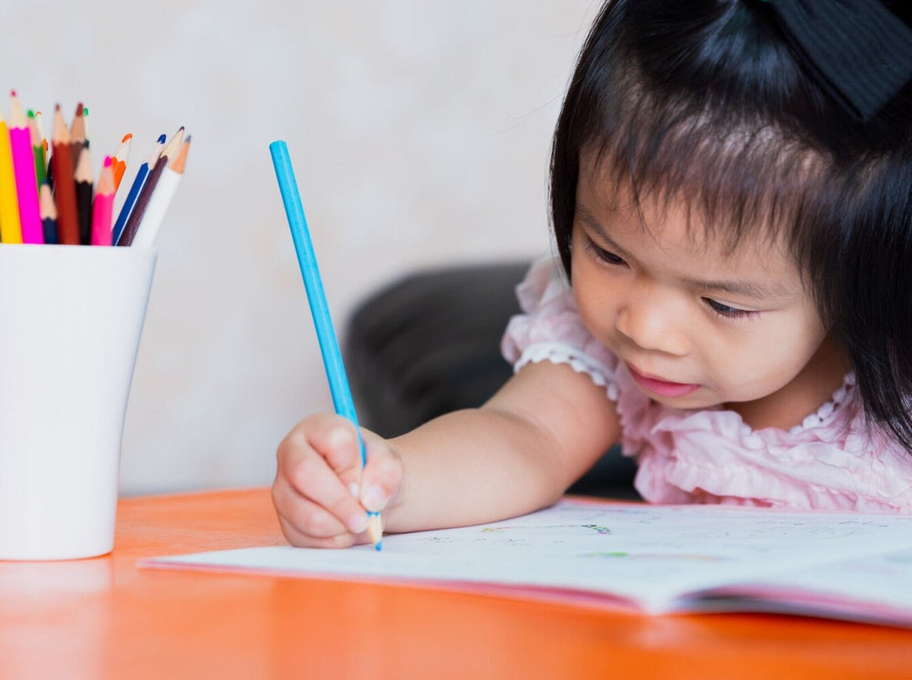young girl doing the best workbooks for 4-year-olds with colorful pencils