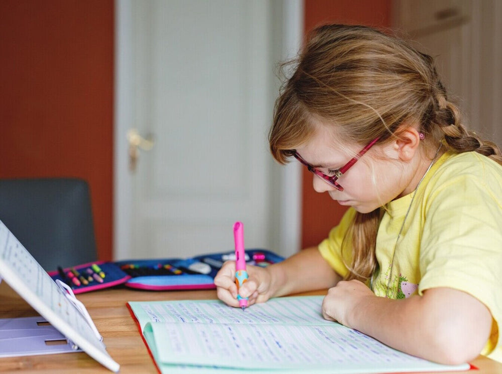 young girl wearing glasses working on some of the best reading comprehension workbooks at home